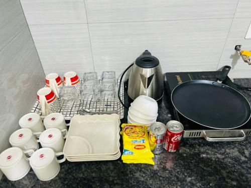 a kitchen counter with cups and a coffee pot and a table at Nivaas Cozy 1BHK Stay near Airport Road in Zirakpur