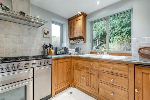a kitchen with wooden cabinets and a stove and a window at Hawkfield in Baslow