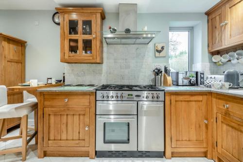 a kitchen with wooden cabinets and a stove top oven at Hawkfield in Baslow