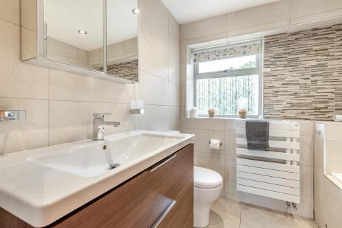 a bathroom with a sink and a toilet and a window at Hawkfield in Baslow