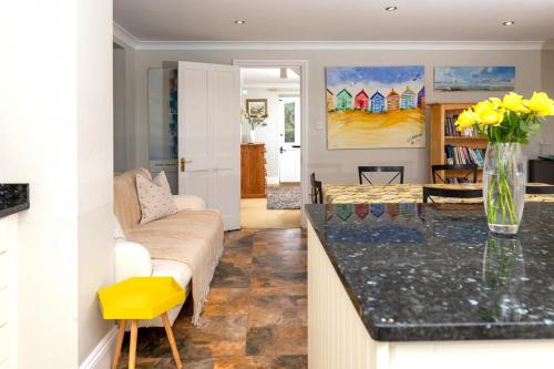 a kitchen and living room with a vase of yellow flowers at Artists Coastal Retreat in Wool