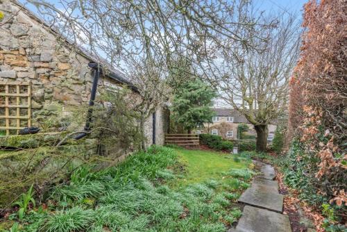 an exterior view of a stone house with a yard at Hawkfield in Baslow