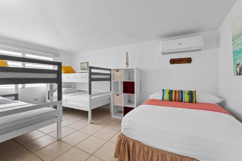 een slaapkamer met een bed en 2 stapelbedden bij La Casita Blanca - Sun in Fajardo