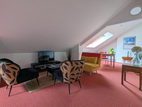a living room with chairs and a couch and a tv at Studio idéalement situé au cœur de la ville et des activités in Loudéac