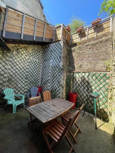 a patio with a wooden table and chairs at Au Cœur d Orgelet in Orgelet