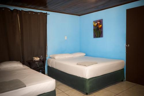 two beds in a room with a blue wall at La Palmera Dorada in Managua