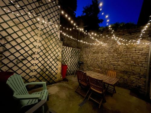 a patio with a table and chairs and lights at Au Cœur d Orgelet in Orgelet