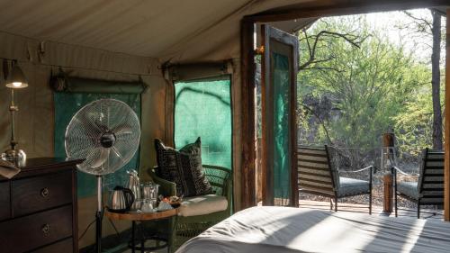 een kamer met een bed, een ventilator en een balkon bij Mashatu Tent Camp in Lentswelemoriti