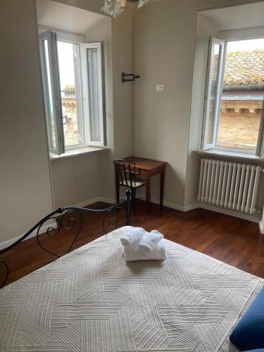 a bedroom with a bed and a table and two windows at Camere al Borgo Affittacamere in Monteprandone