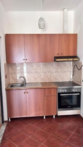 a kitchen with wooden cabinets and a sink and a stove at A&S Hotel in Lezhë