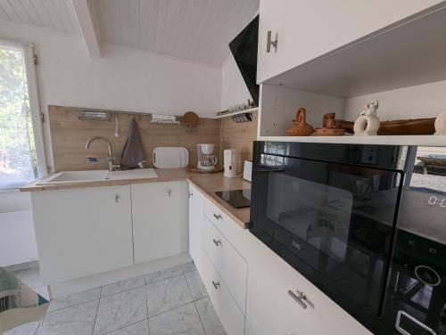 a kitchen with white cabinets and a black stove top oven at Maison du Marais Vendéen in Saint-Benoist-sur-Mer