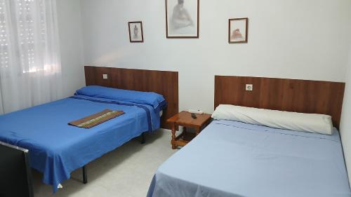 a room with two beds and a table in it at Habitacion Privada Familiar Toledo in Toledo