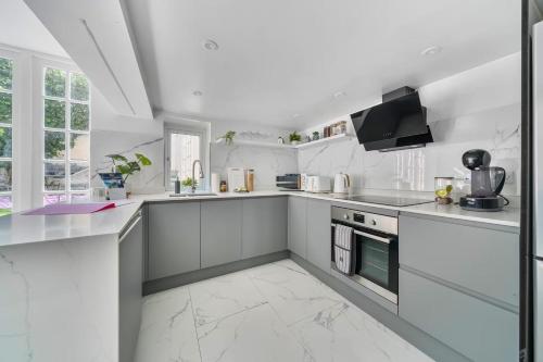 a white kitchen with white cabinets and appliances at Georgian Coach House in a Prime Location in Deal in Kent