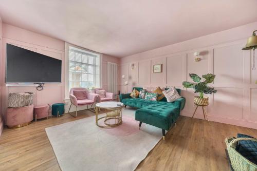 a living room with a green couch and pink walls at Georgian Coach House in a Prime Location in Deal in Kent