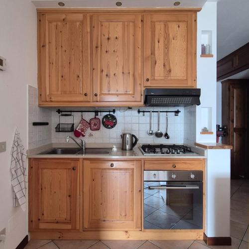 a kitchen with wooden cabinets and a stove at Le Terrazze del Sagittario - Top View - PVT Parking in Prato Nevoso