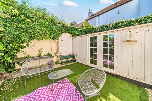 a backyard with two chairs and a table and a rug at Georgian Coach House in a Prime Location in Deal in Kent