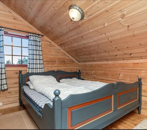 ein Schlafzimmer mit einem Bett in einer Blockhütte in der Unterkunft Karíbu-Welcome in Øyuvstad