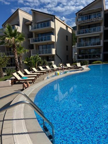 a swimming pool with lounge chairs and a building at Teuta Azure Apartment - Blue Horizont Complex, Sveti Stefan in Pržno