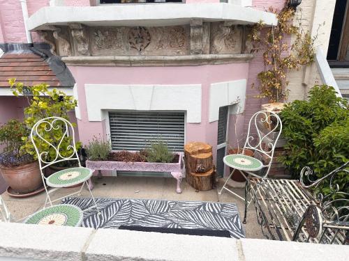 two chairs and a table in front of a pink building at La Di Da Hotel beach town in Bournemouth