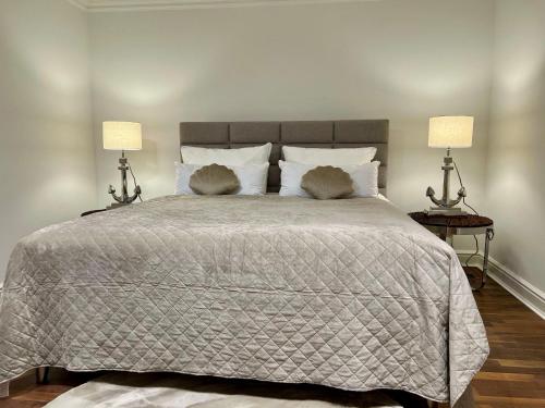 a bedroom with a large bed with two lamps at Hygge Suite Sylt Kampen in Niederdorla