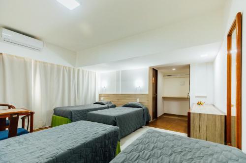 a hotel room with three beds and a table at El Aram Beach Boa Viagem in Recife