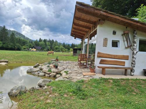 a house with a bench next to a pond at Froschteichhäuschen in Spitzwiesen