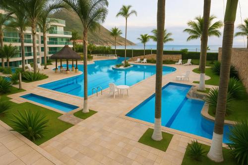 an aerial view of a resort swimming pool with palm trees at Apart completo RESORT Pé na Areia RECREIO in Rio de Janeiro