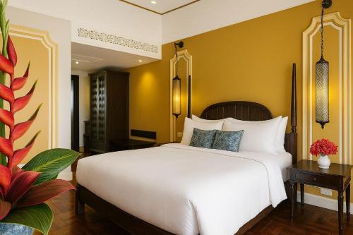 a bedroom with a large white bed and yellow walls at The Grand Luang Prabang, Affiliated by Meliá in Luang Prabang