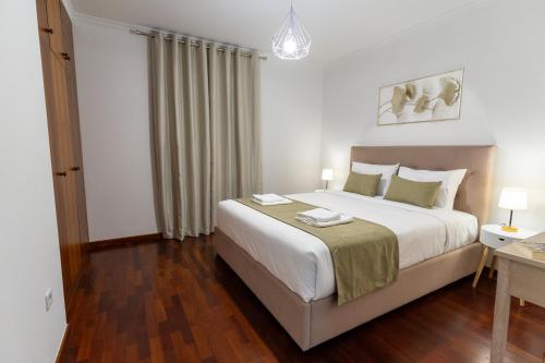 a bedroom with a large white bed and a desk at Apartamento Isabel Charmoso e bem localizado in Ribeira Brava