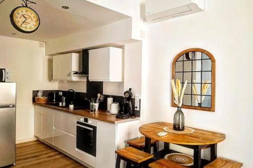 une cuisine avec une table et une horloge au mur dans l'établissement 34 m avec wifi proche des PLAGES du Mourillon, à Toulon