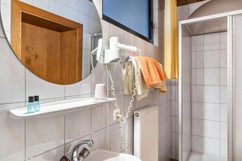 a bathroom with a mirror and a sink at Pension Heidelberg in Hopfgarten im Brixental