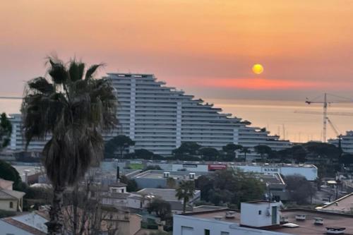 un grand bâtiment avec un palmier devant un coucher de soleil dans l'établissement BRAND NEW 2 BR in Villeneuve-Loubet sea view terrasse & parking - BENAKEY, à Villeneuve-Loubet