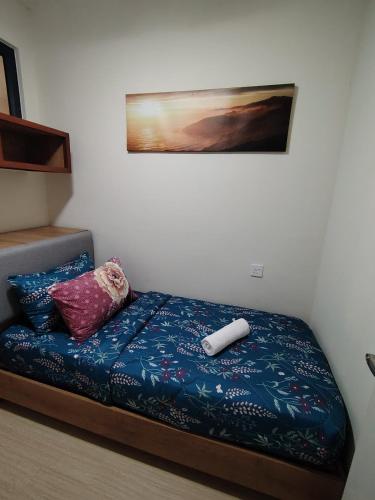 a bed in a room with a blue blanket and pillows at Timurbay Seafront By Moonlight in Kuantan