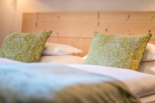 a bedroom with two beds with green and white pillows at Gasthof Traube in San Lorenzo di Sebato