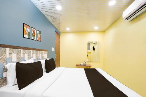 a bedroom with a large white bed with black pillows at Hotel O Pragati in Jairāmpura