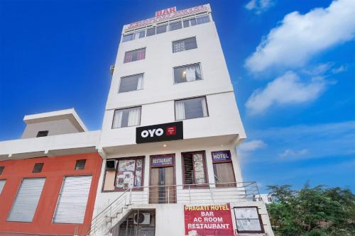 a tall white building with a sign on it at Hotel O Pragati in Jairāmpura