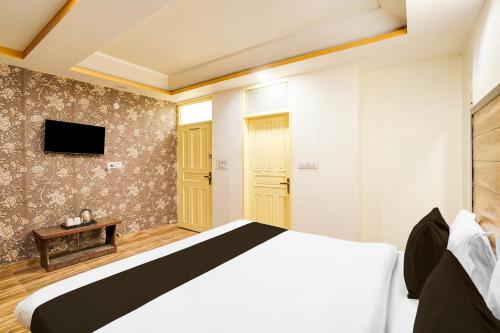 a bedroom with a white bed and a tv at Hotel O Pragati in Jairāmpura