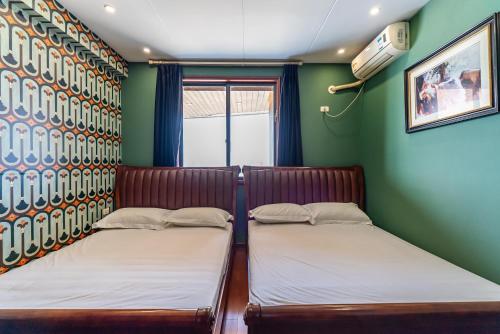 two beds in a room with green walls at Misty Nest High Altitude River View B&B Hongyadong Branch in Chongqing