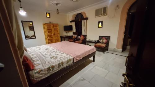 a bedroom with a bed and a desk and chair at Kanhaia Haveli in Pushkar
