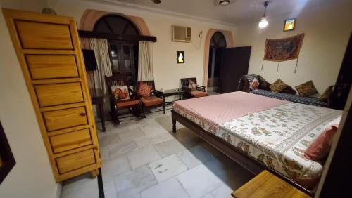 a bedroom with a bed and a dresser and chairs at Kanhaia Haveli in Pushkar