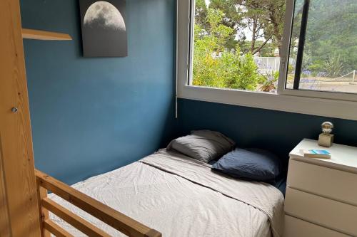 Ce lit se trouve dans un dortoir bleu doté d'une fenêtre. dans l'établissement Charming T1 on the seafront, à La Baule