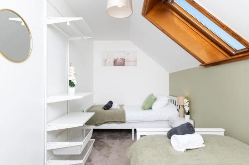 Una habitación blanca con una cama y un espejo. en The Steading, Kingsbarns., en Kingsbarns