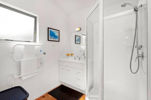 a white bathroom with a shower and a sink at HORIZON SURF LODGE plus private spa in Raglan