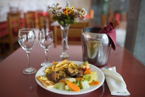 a plate of food on a table with wine glasses at Panorama Hotel in Juazeiro do Norte
