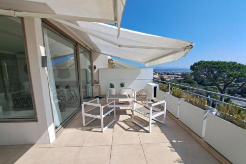 - un balcon avec une table et des chaises sous un parasol dans l'établissement BRAND NEW 2 BR in Villeneuve-Loubet sea view terrasse & parking - BENAKEY, à Villeneuve-Loubet