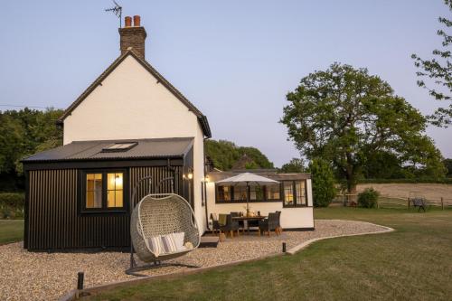 a black and white tiny house with a swing at Historic Farmhouse Retreat Foot of the South Downs in Wivelsfield