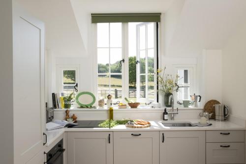 eine weiße Küche mit Spüle und Fenster in der Unterkunft Historic Farmhouse Retreat Foot of the South Downs in Wivelsfield