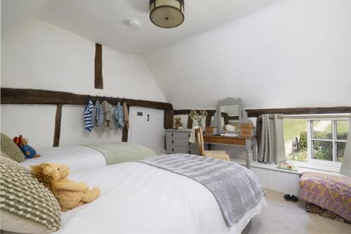 ein Schlafzimmer mit einem weißen Bett mit einem Teddybär darauf in der Unterkunft Historic Farmhouse Retreat Foot of the South Downs in Wivelsfield