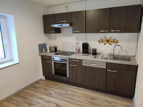 a kitchen with wooden cabinets and a sink and a stove at Ferienwohnung Pferdehof in Gunzenhausen