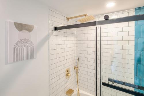a bathroom with a shower with white tiles at Chic 1BR plus Den Condo with Fast WiFi and Free Parking in Toronto